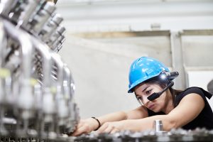 Woman inspecting bottling machine wearing smart glasses and safety helmet Copyright TeamViewer