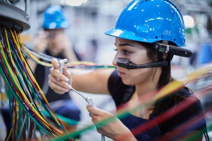 Woman maintaining electrics from bottling machine wearing smart glasses and safety helmet Copyright TeamViewer